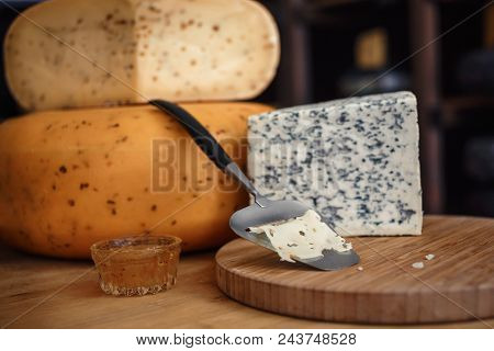 Cheese Heads With Slices And Knives Lie On A Wooden Board With An Interior