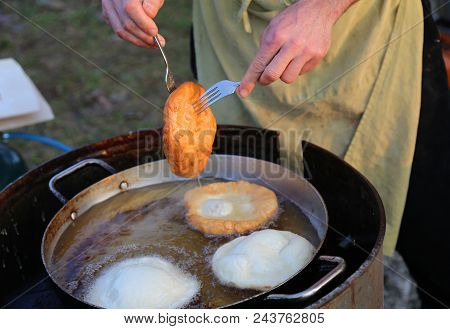 Cook While Cooking Some Sweet Pancakes In The Pot With Boiling Oil