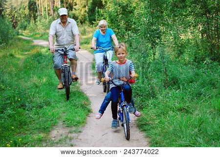 Active Senior Couple With Kids Riding Bikes In Nature, Grandparenting