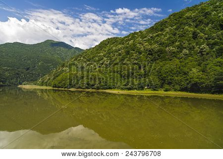 Landscape With Olt River In Romania Surrounded By Forest And Mountains