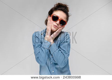Young Girl With Glasses In Heart On Gray Background. Portrait Of A Young Beautiful Girl. Charming Gi