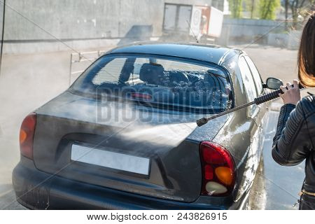 Young Woman Washing Car At Self-service Carwash