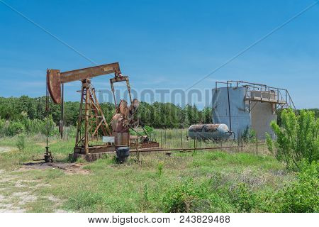 Working Pump Jack Pumping Crude Oil At Oil Drilling Site In Rural Usa
