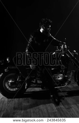 Man With Beard, Biker In Leather Jacket Lean On Motor Bike In Darkness, Black Background. Macho, Bru