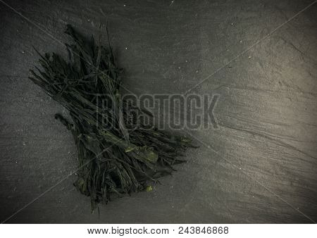 Heap Of Dry Wakame Seaweed On Black Stone Background. Healthy Algae Food With Place For Text