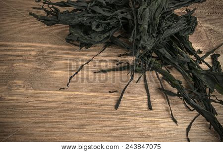 Heap Of Dry Wakame Seaweed On Wooden Background. Healthy Algae Food With Place For Text