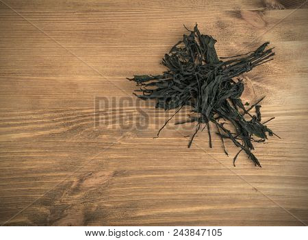 Heap Of Dry Wakame Seaweed On Wooden Background. Healthy Algae Food With Place For Text