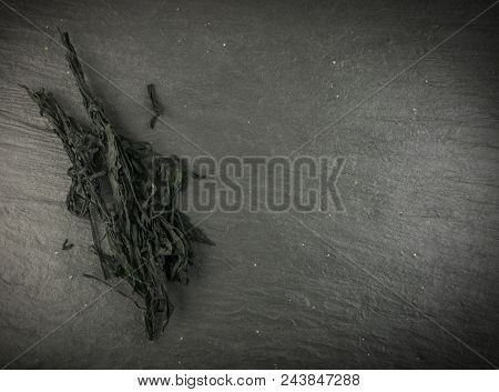 Heap Of Dry Wakame Seaweed On Black Stone Background. Healthy Algae Food With Place For Text