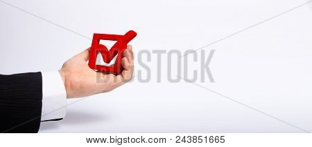 A Man Who Is Unemployed In A Business Suit Is Holding A Wooden Box. A Tick In The Box. The Hand Hold