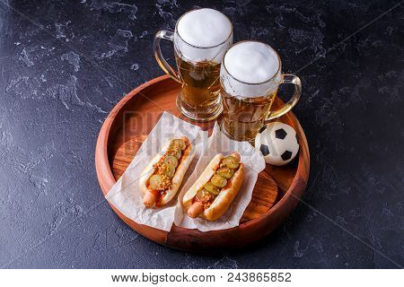 Photo On Top Of Two Glasses Of Beer And Hot Dogs On Wooden Tray With Football On Wooden Background