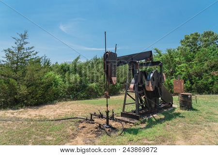 Working Pump Jack Pumping Crude Oil At Oil Drilling Site In Rural Usa