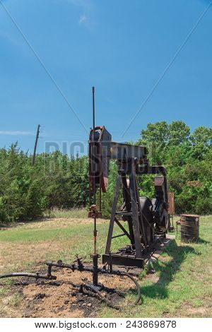 Working Pump Jack Pumping Crude Oil At Oil Drilling Site In Rural Usa