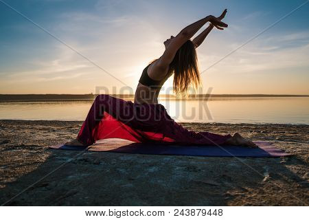 Silhouette Woman On The Beach At Sunset Doing Yoga Asana. Morning Natural Stretch Warm-up Training
