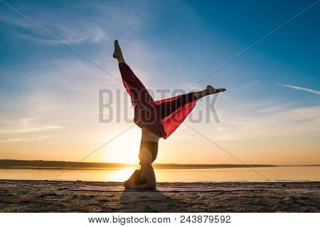 Silhouette Woman On The Beach At Sunset Doing Yoga Asana. Morning Natural Stretch Warm-up Training