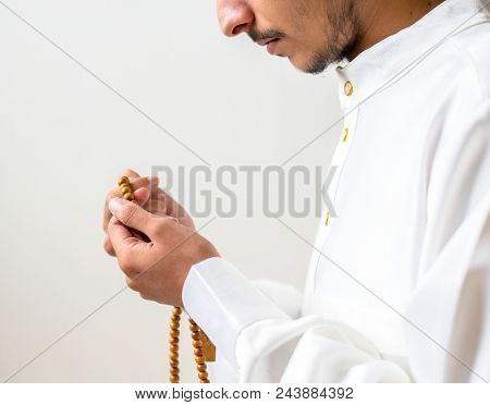 Muslim man using misbaha to keep track of counting in tasbih