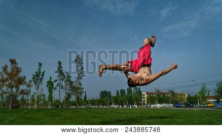 Tricking On Lawn In Park. Man Does Somersault Ahead. Martial Arts And Parkour. Street Workout.