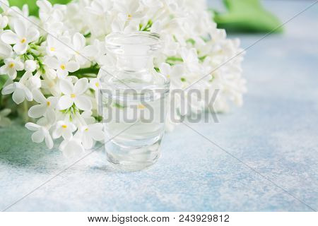 Lilac Fragnance In Glass Perfume Bottle With White Lilac On Blue Background, Closeup View With Copy 