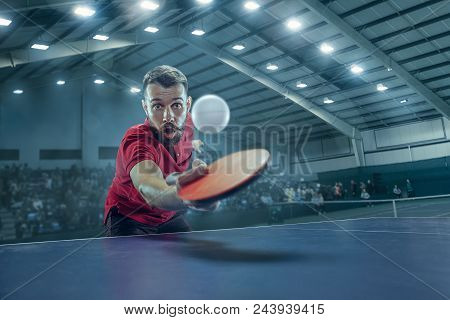 The Table Tennis Player In Motion. Fit Young Sports Man Tennis-player In Play On Sport Arena Backgro