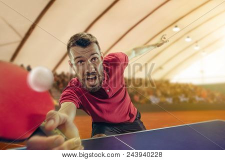 The Table Tennis Player In Motion. Fit Young Sports Man Tennis-player In Play On Sport Arena Backgro