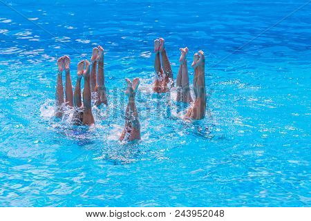 Synchronised Swimming. Beautiful Lean Female Legs In The Water Of A Swimming Pool. Concept Of Beauty