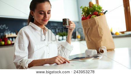 Young woman planning expenses and paying bills on her kitchen