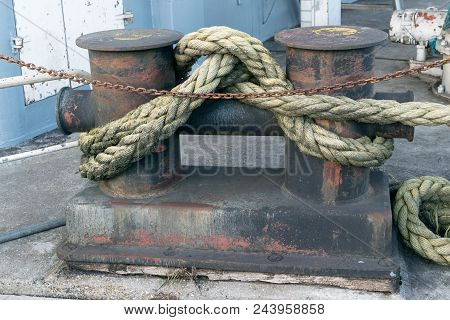 Close Up Of An Old Rusty Metal Bollard. Rusty Industrial Metal Chain. Background For Design