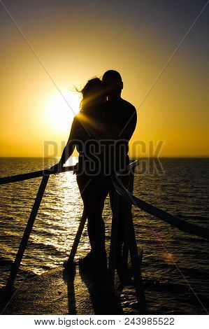 Silhouette Of Young Couple On Yacht Over The Orange Sea Sunset. Romantic And Love Concept.