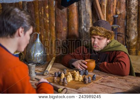 Portrait Of Man In Russian Ethnic Suit Playing Board Game Like Chess. Folk, Competition And Traditio