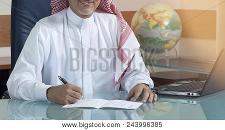 Senior Saudi Businessman Hand Writing At His Desk