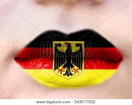 Female Lips Close Up With A Picture Flag Of Germany. Learning Languages.