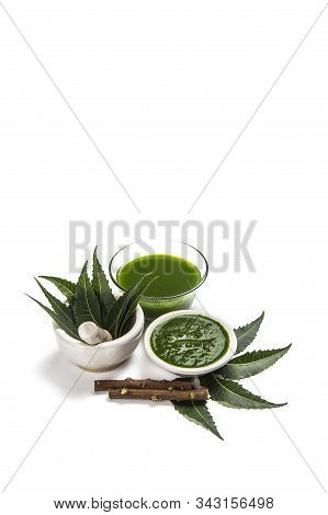 Medicinal Neem Leaves In Mortar And Pestle With Neem Paste, Juice And Twigs On White Background