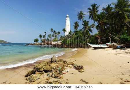 Bellissimo faro bianco Dondra Head, il capo sud dello Sri Lanka - visto dalla spiaggia. Il li