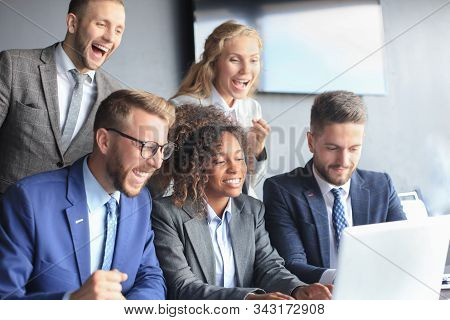 Happy Business People Laugh Near Laptop In The Office. Successful Team Coworkers Joke And Have Fun T