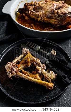 A Plate Of Chicken Bones And A Chicken Skeleton In A Baking Dish. Leftovers From Dinner. Black Backg