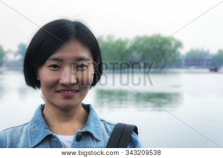 A Chinese Woman Smiling In Front Of Qianhai Lake In Hutong Scenic Area Of Beijing China On An Overca