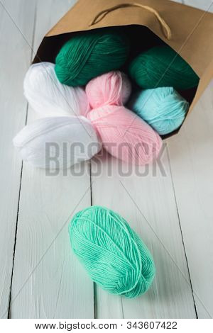 Scatter Oval Acrylic Colorful Wool Yarn Thread Skeins Lying With Kraft Paper Brown Package On White 