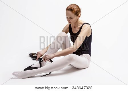 Portrait Of Tranquil Caucasian Professional Ballet Dancer In Body Suit  And Pointes Shoes Posing Aga
