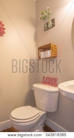 Vertical Frame Bathroom Interior With Toliet Adjacent To Stand Alone Sink And Round Mirror