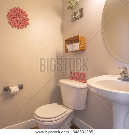 Square Frame Bathroom Interior With Toliet Adjacent To Stand Alone Sink And Round Mirror