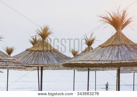 Sun Umbrellas And Beach Beds On The Sea Coast.sun Beds With A Thatched Roof On The Seashore.