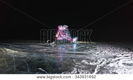Young Loving Couple Skating At Ice Rink At Night. Man And Woman Kiss Hug Have Fun Learn To Skate. Ma