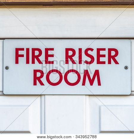 Square Close Up Of The Fire Riser Room With White Wooden Door Of A Brick Building