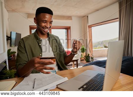Young Adult Black Male Excited About Making Online Purchase On Laptop In Modern Apartment.