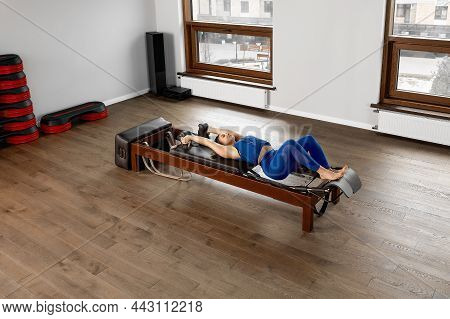 The Instructor Does Exercises On The Reformer, A Beautiful Girl Trains On The Modern Reformer Simula
