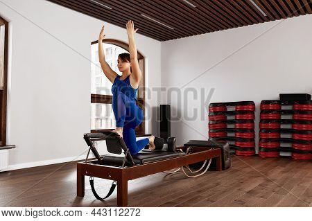 The Instructor Does Exercises On The Reformer, A Beautiful Girl Trains On The Modern Reformer Simula
