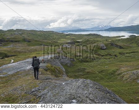 Man Hiker With Backpack Walking At Footpath In Lapland Landscape At Virihaure Lake With Green Mounta