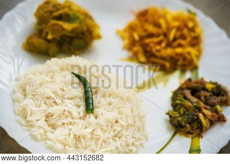 Typical Bengali Thali Background Containing Rice, Dal, Potato Fries, Vegetable Curry & A Green Chill
