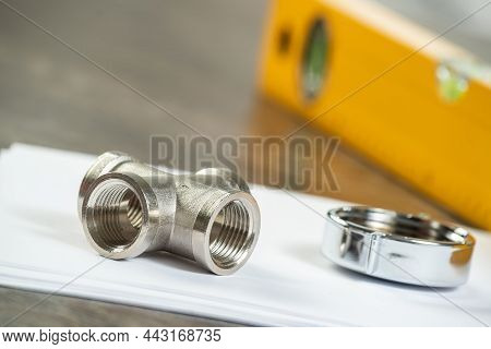 Steel Water Fittings For Hydraulic System. Plumbing Pipeline Parts And Level Tool Laying On Table. B