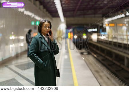 Young African American Woman Office Worker Making Phonecall While Standing At Subway Platform After 