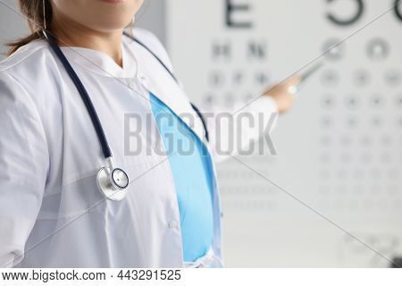 Close-up Of Female Eye Doctor Point On Letter On Eye Test Chart. Optician In Uniform, Appointment In